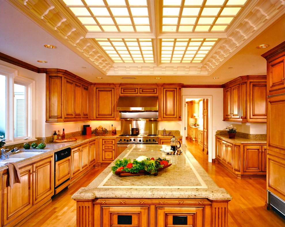 На фото: кухня в классическом стиле с техникой из нержавеющей стали, фасадами с выступающей филенкой и фасадами цвета дерева среднего тона с