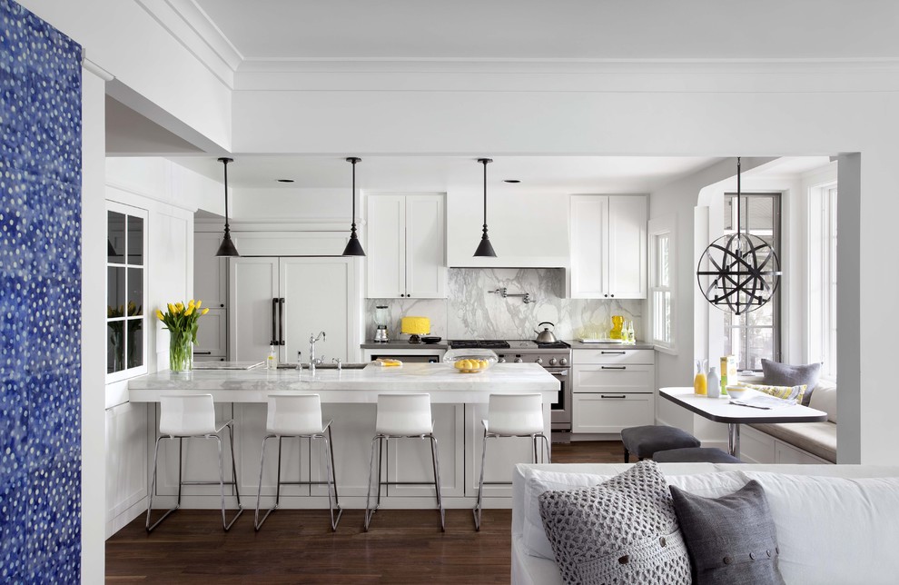 На фото: параллельная кухня-гостиная в классическом стиле с техникой под мебельный фасад, белыми фасадами, мраморной столешницей, белым фартуком, фартуком из каменной плиты и фасадами с утопленной филенкой с