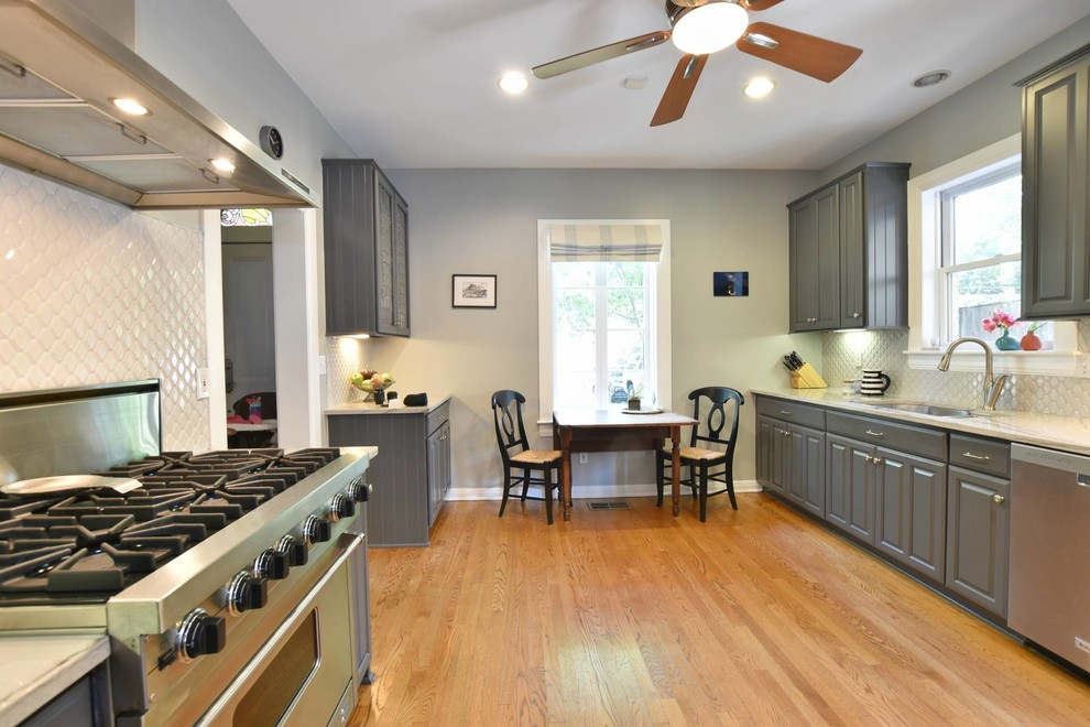 Exempel på ett avskilt, litet klassiskt kök, med en undermonterad diskho, luckor med profilerade fronter, grå skåp, bänkskiva i kvartsit, grått stänkskydd, stänkskydd i mosaik, rostfria vitvaror, mellanmörkt trägolv och brunt golv