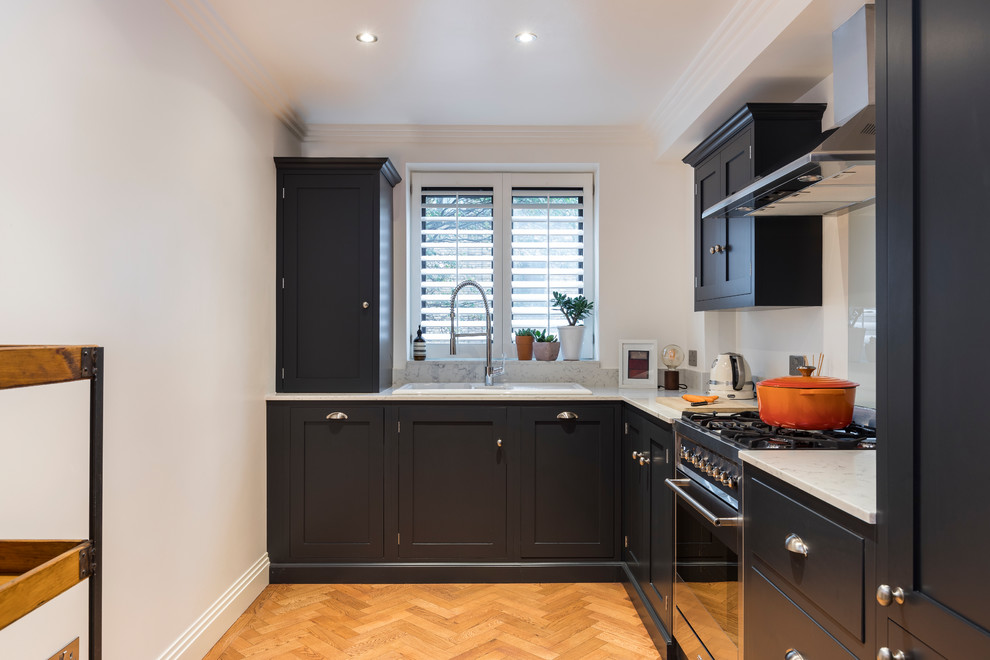 Design ideas for a small traditional l-shaped kitchen in London with a built-in sink, recessed-panel cabinets, blue cabinets, marble worktops, marble splashback, medium hardwood flooring and brown floors.