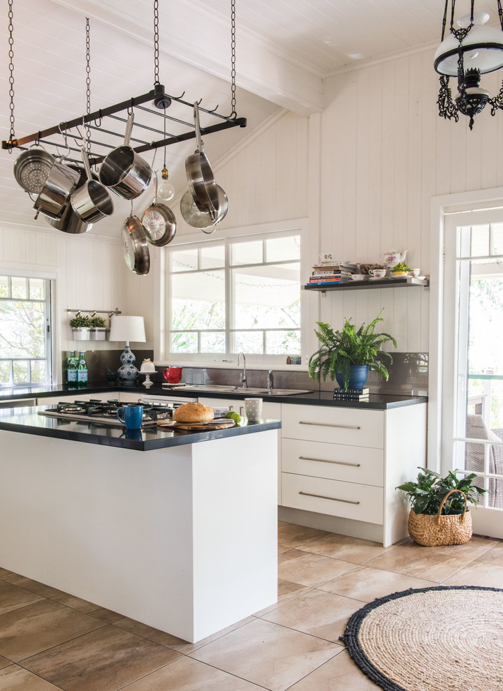 Example of a mid-sized farmhouse l-shaped porcelain tile open concept kitchen design in Brisbane with a double-bowl sink, flat-panel cabinets, white cabinets, granite countertops, glass sheet backsplash, stainless steel appliances, an island and gray backsplash