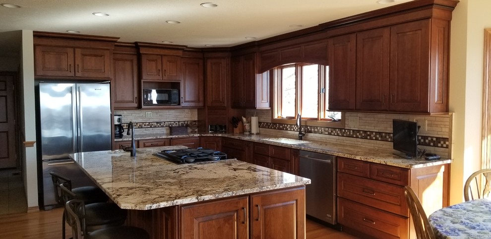 Klassische Küche mit Doppelwaschbecken, Granit-Arbeitsplatte, Küchengeräten aus Edelstahl und braunem Holzboden in Sonstige
