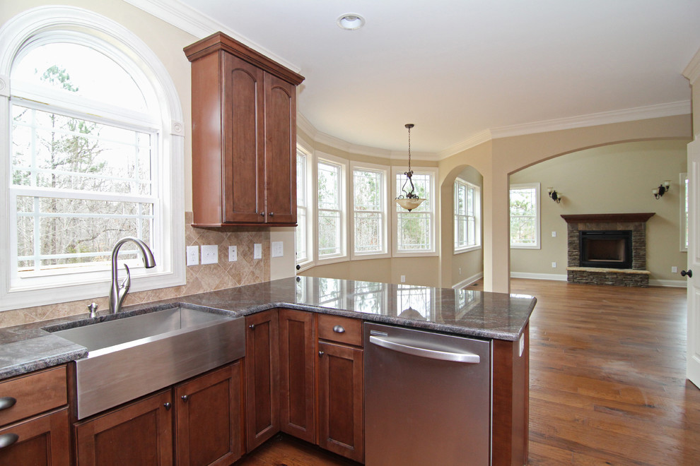Mid-sized elegant l-shaped medium tone wood floor open concept kitchen photo in Raleigh with a single-bowl sink, recessed-panel cabinets, medium tone wood cabinets, granite countertops, beige backsplash, ceramic backsplash, stainless steel appliances and a peninsula