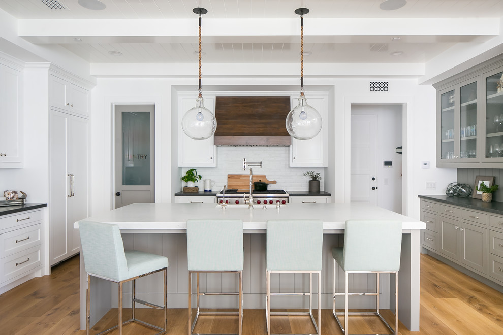 Maritime Küche mit Glasfronten, grauen Schränken, Küchenrückwand in Weiß, Elektrogeräten mit Frontblende, hellem Holzboden und Kücheninsel in Orange County