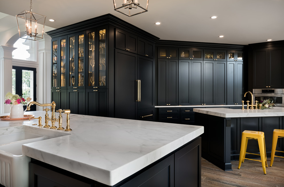 Inspiration for a large transitional l-shaped light wood floor eat-in kitchen remodel in Charlotte with a farmhouse sink, recessed-panel cabinets, blue cabinets, marble countertops, white backsplash, subway tile backsplash, paneled appliances and two islands