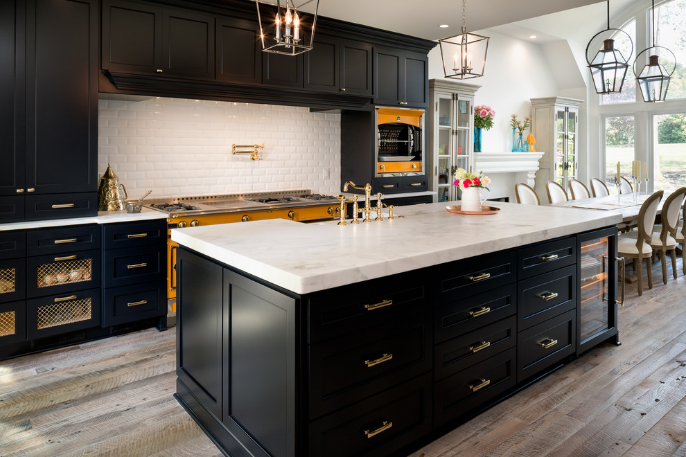 Large elegant galley light wood floor eat-in kitchen photo in Charlotte with a farmhouse sink, recessed-panel cabinets, white backsplash, subway tile backsplash, colored appliances and an island