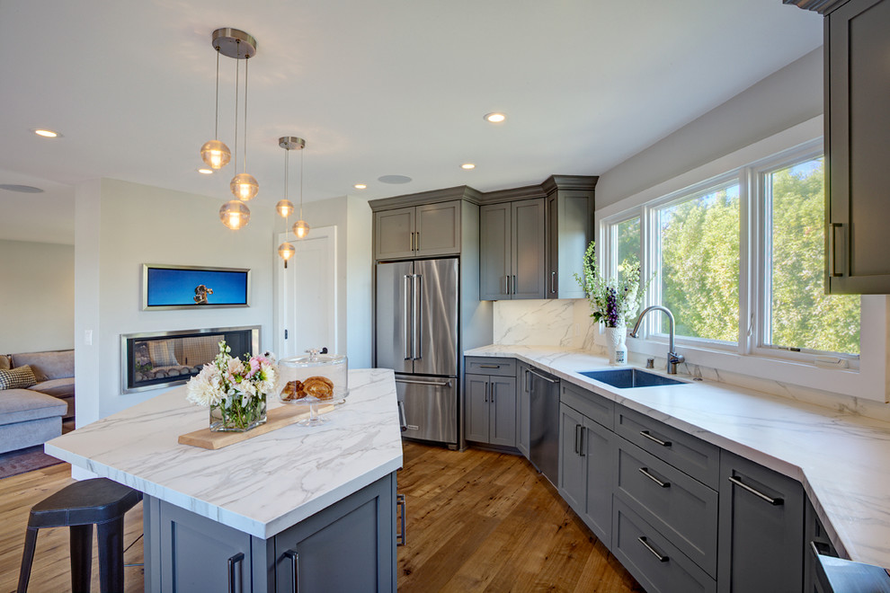 Inspiration for a mid-sized contemporary u-shaped medium tone wood floor open concept kitchen remodel in San Francisco with an undermount sink, shaker cabinets, gray cabinets, quartz countertops, white backsplash, stone slab backsplash, stainless steel appliances and an island