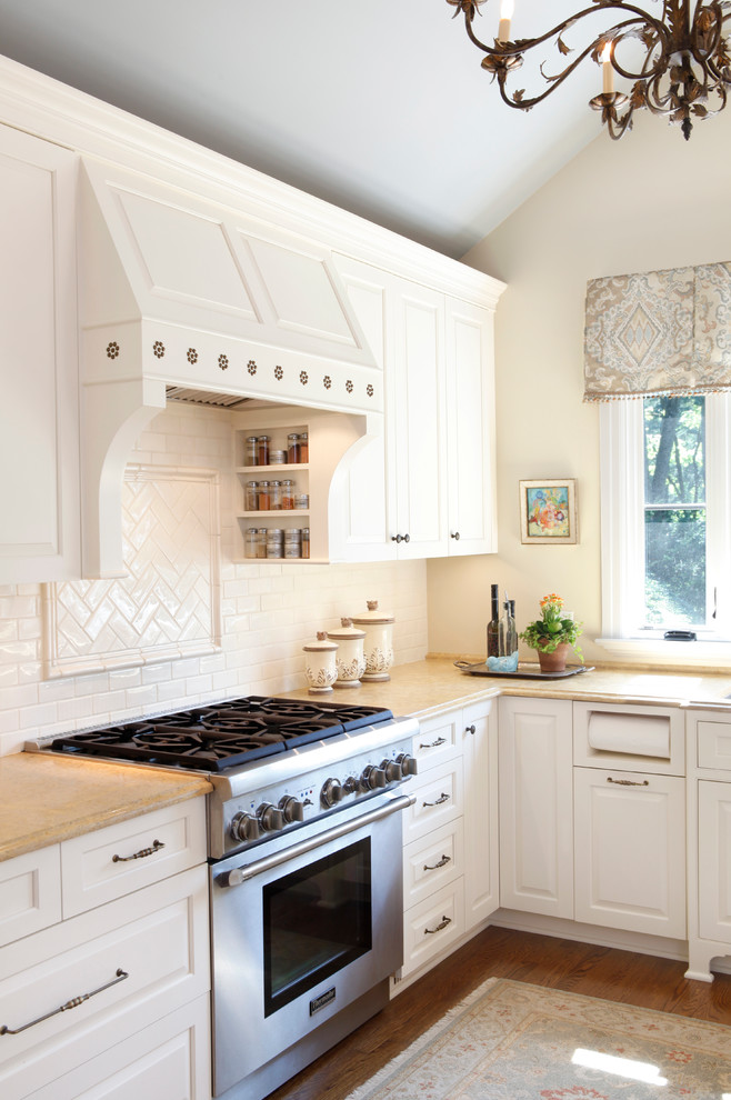 Inredning av ett klassiskt mellanstort kök, med en undermonterad diskho, luckor med upphöjd panel, beige skåp, marmorbänkskiva, beige stänkskydd, stänkskydd i porslinskakel, rostfria vitvaror, mellanmörkt trägolv och en halv köksö