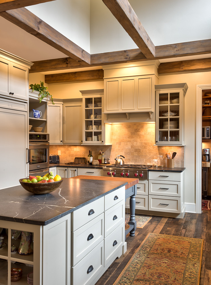 Country l-shaped kitchen/diner in Other with soapstone worktops, multiple islands, shaker cabinets, white cabinets, beige splashback, stainless steel appliances, dark hardwood flooring, a submerged sink and limestone splashback.