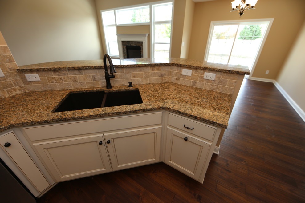 Exempel på ett mellanstort amerikanskt kök, med granitbänkskiva, rostfria vitvaror, en dubbel diskho, luckor med infälld panel, skåp i mörkt trä, beige stänkskydd, stänkskydd i stenkakel, klinkergolv i porslin och en halv köksö