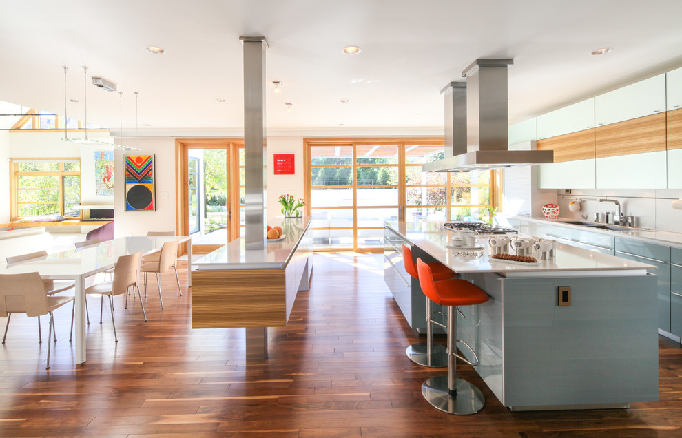Foto di una cucina ad ambiente unico design con lavello a doppia vasca, ante lisce, ante blu, pavimento in legno massello medio, 2 o più isole e pavimento arancione
