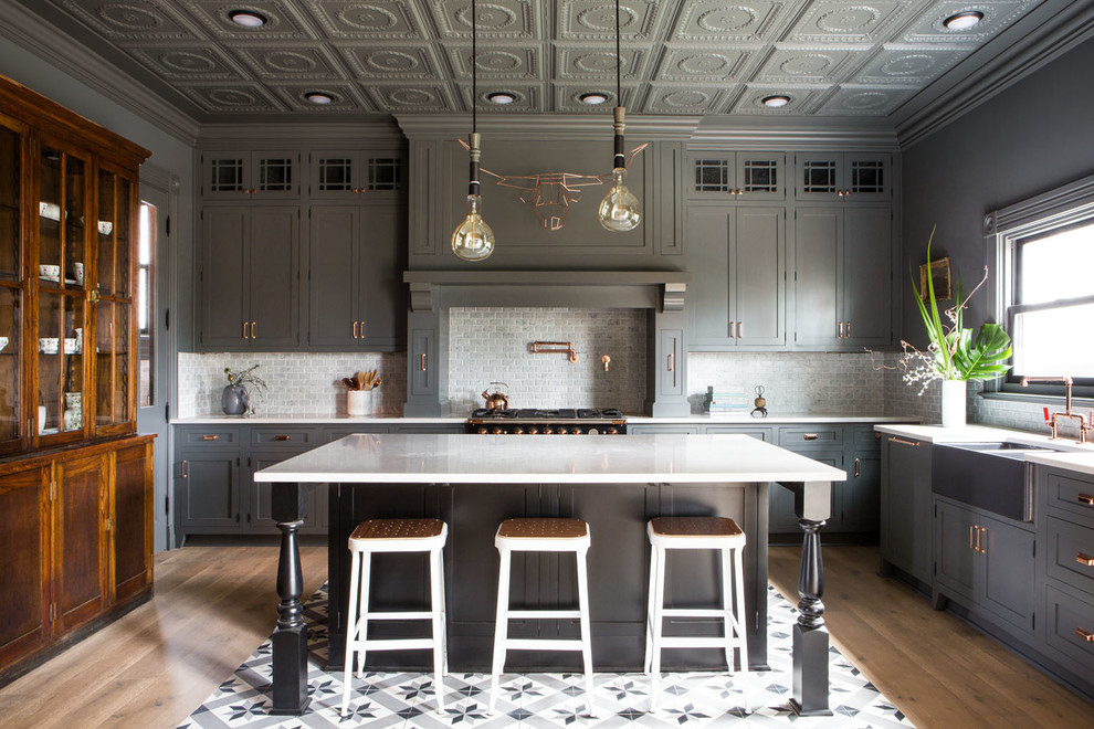 Klassische Küche in L-Form mit Landhausspüle, Schrankfronten im Shaker-Stil, grauen Schränken, Küchenrückwand in Grau, Rückwand aus Metrofliesen, Kücheninsel, buntem Boden und weißer Arbeitsplatte in Portland