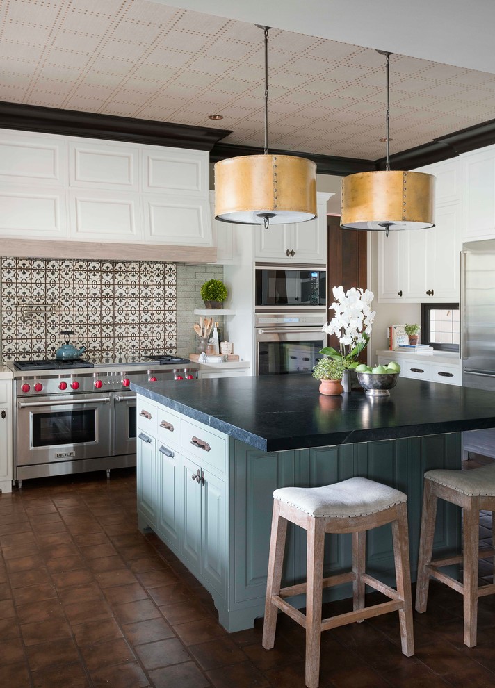 Bild på ett mellanstort vintage kök, med flerfärgad stänkskydd, en rustik diskho, luckor med upphöjd panel, vita skåp, stänkskydd i terrakottakakel, rostfria vitvaror och en köksö