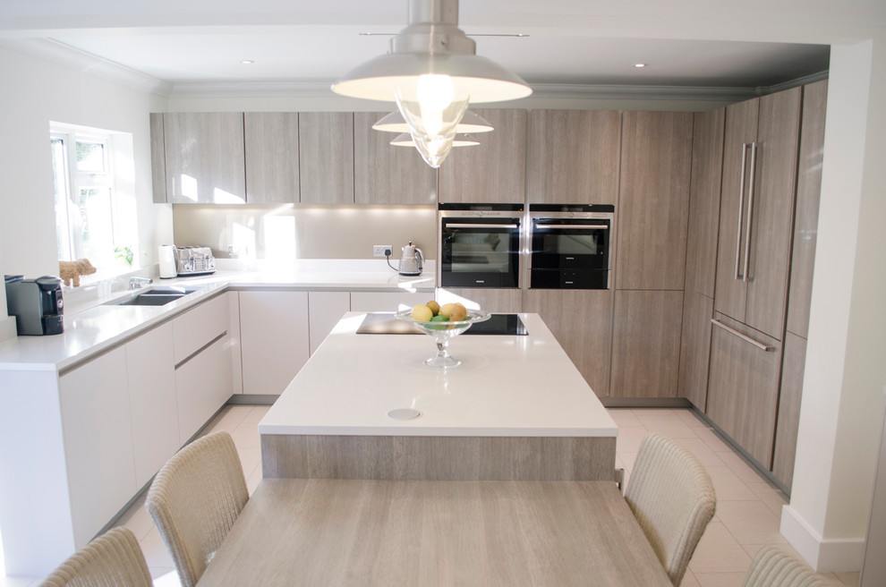 Medium sized modern u-shaped kitchen/diner in London with a double-bowl sink, flat-panel cabinets, light wood cabinets, marble worktops, integrated appliances, ceramic flooring and an island.