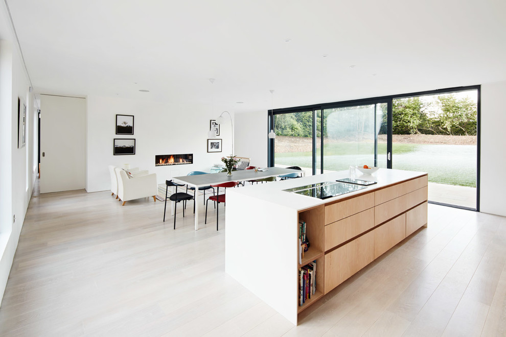 Diseño de cocina moderna abierta con armarios con paneles lisos, puertas de armario de madera clara, suelo de madera clara y una isla