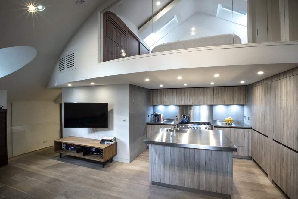 Mid-sized trendy l-shaped light wood floor open concept kitchen photo in London with a drop-in sink, flat-panel cabinets, stainless steel countertops, gray backsplash, cement tile backsplash, paneled appliances and a peninsula
