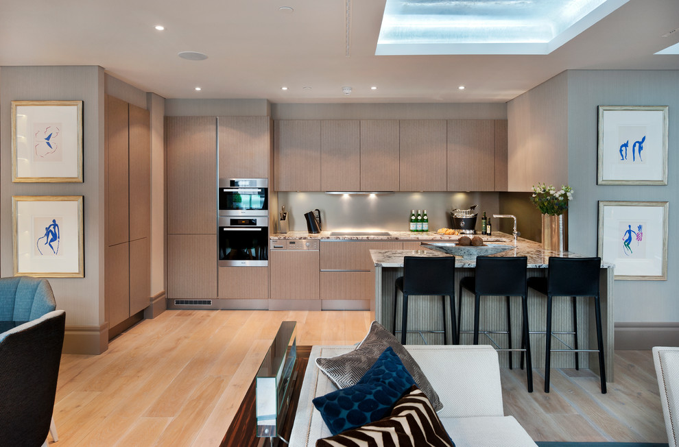 Photo of a medium sized contemporary u-shaped kitchen in London with a submerged sink, flat-panel cabinets, light wood cabinets, medium hardwood flooring, a breakfast bar, beige floors and grey worktops.