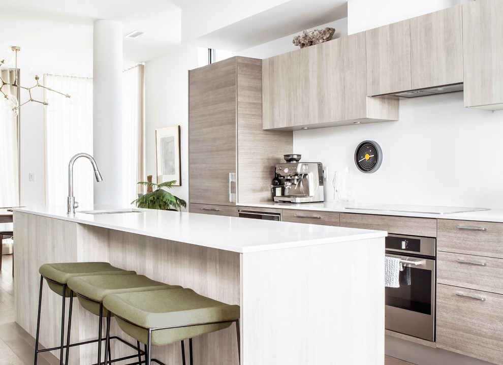 Стильный дизайн: параллельная кухня-гостиная в современном стиле с врезной мойкой, плоскими фасадами, серыми фасадами, белым фартуком, техникой из нержавеющей стали, островом и белой столешницей - последний тренд