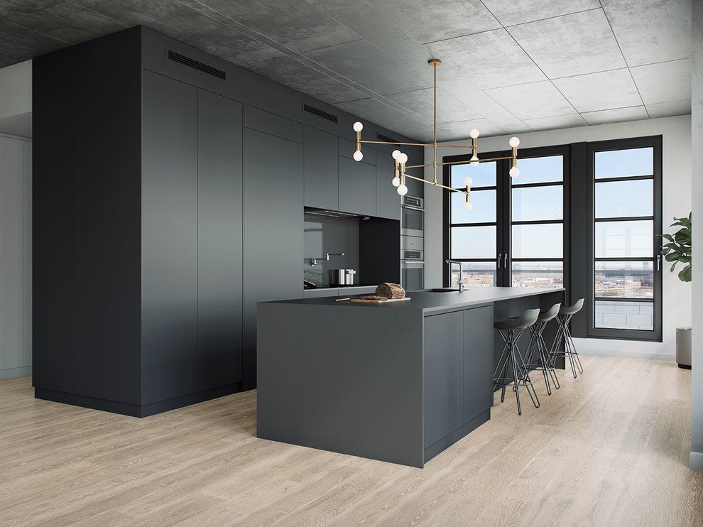 This is an example of a large modern kitchen in Montreal with flat-panel cabinets, grey cabinets, laminate countertops, glass tiled splashback, light hardwood flooring, an island, grey splashback and stainless steel appliances.