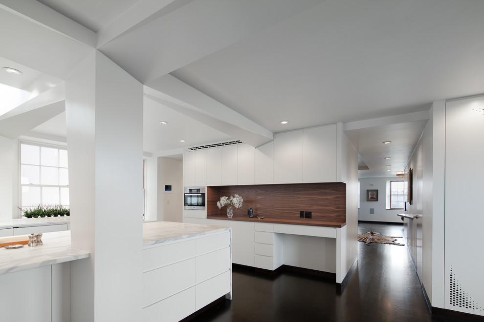 Large modern galley kitchen/diner in Boston with a submerged sink, flat-panel cabinets, white cabinets, marble worktops, white appliances, dark hardwood flooring and an island.