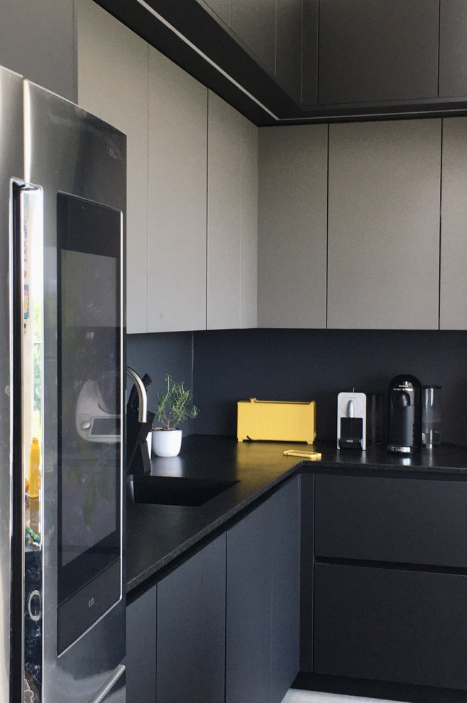 Modern inredning av ett mellanstort svart svart kök, med en nedsänkt diskho, släta luckor, svarta skåp, bänkskiva i koppar, svart stänkskydd, rostfria vitvaror, målat trägolv, en köksö och grått golv