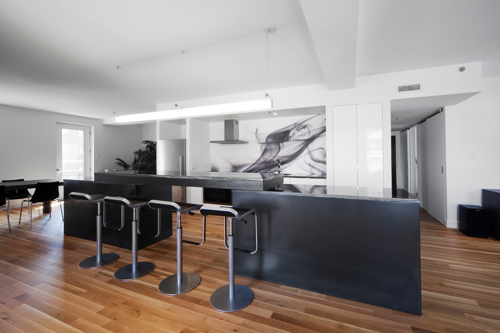 Свежая идея для дизайна: прямая кухня-гостиная в современном стиле с черным фартуком, техникой из нержавеющей стали, фартуком из стекла и черно-белыми фасадами - отличное фото интерьера