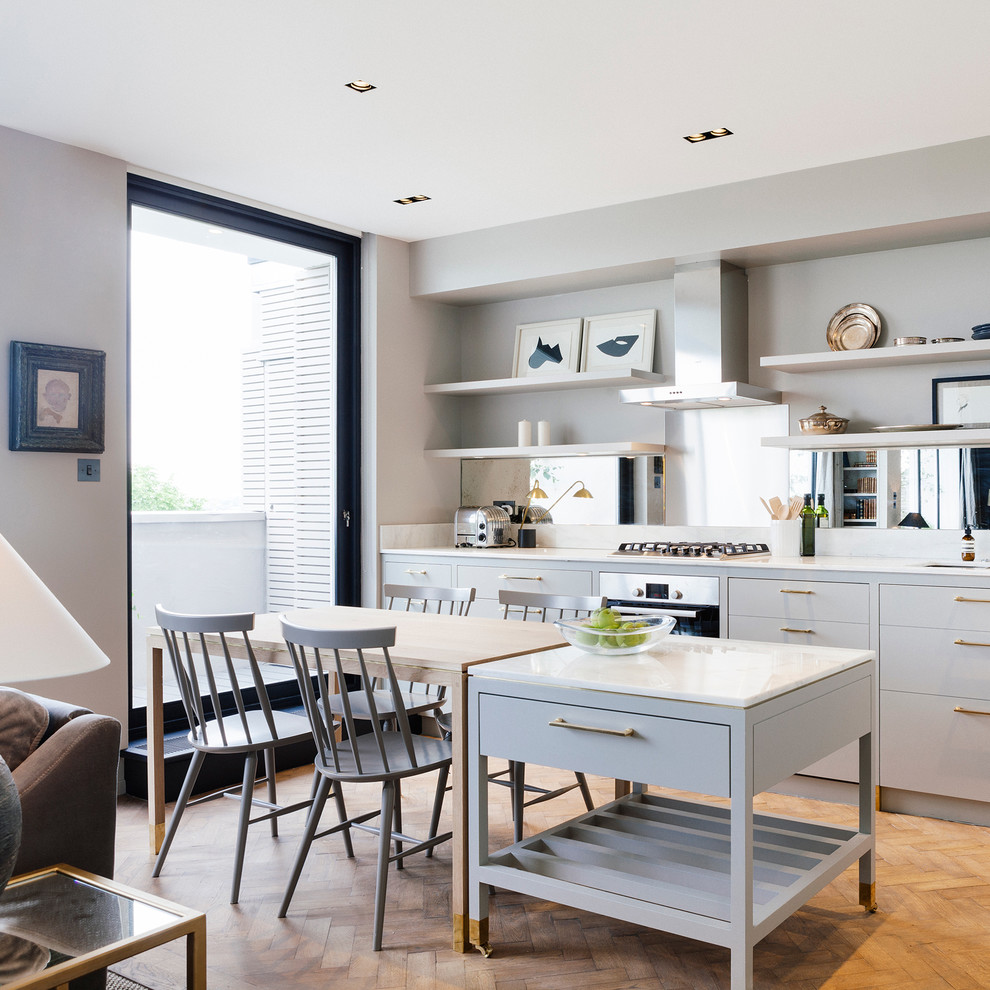 Foto på ett litet funkis linjärt kök och matrum, med grå skåp, marmorbänkskiva, stänkskydd med metallisk yta, spegel som stänkskydd, integrerade vitvaror, mellanmörkt trägolv och en köksö