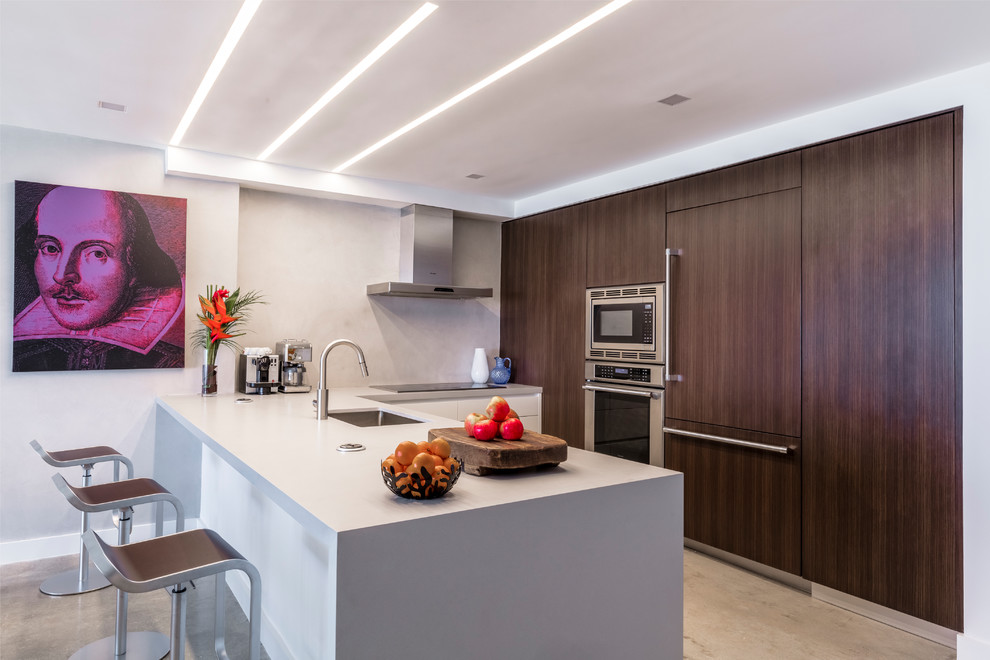 Eat-in kitchen - mid-sized modern u-shaped concrete floor and gray floor eat-in kitchen idea in Miami with an undermount sink, flat-panel cabinets, dark wood cabinets, quartz countertops, gray backsplash, stone slab backsplash, paneled appliances, a peninsula and gray countertops