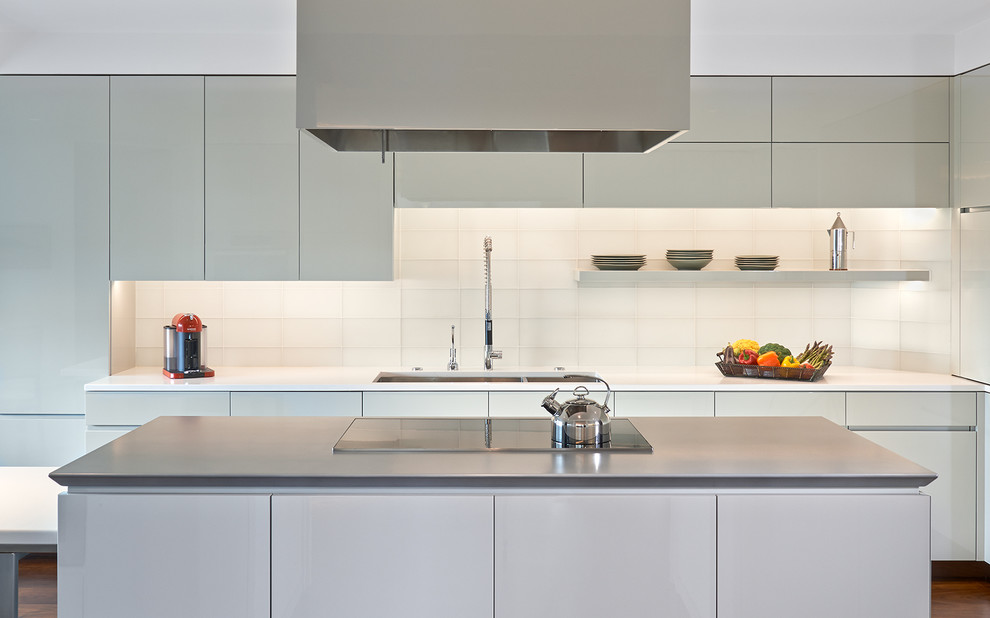 Exempel på ett stort modernt kök, med släta luckor, mörkt trägolv, en köksö, en dubbel diskho, vita skåp, bänkskiva i kvarts, integrerade vitvaror, vitt stänkskydd, stänkskydd i glaskakel och brunt golv