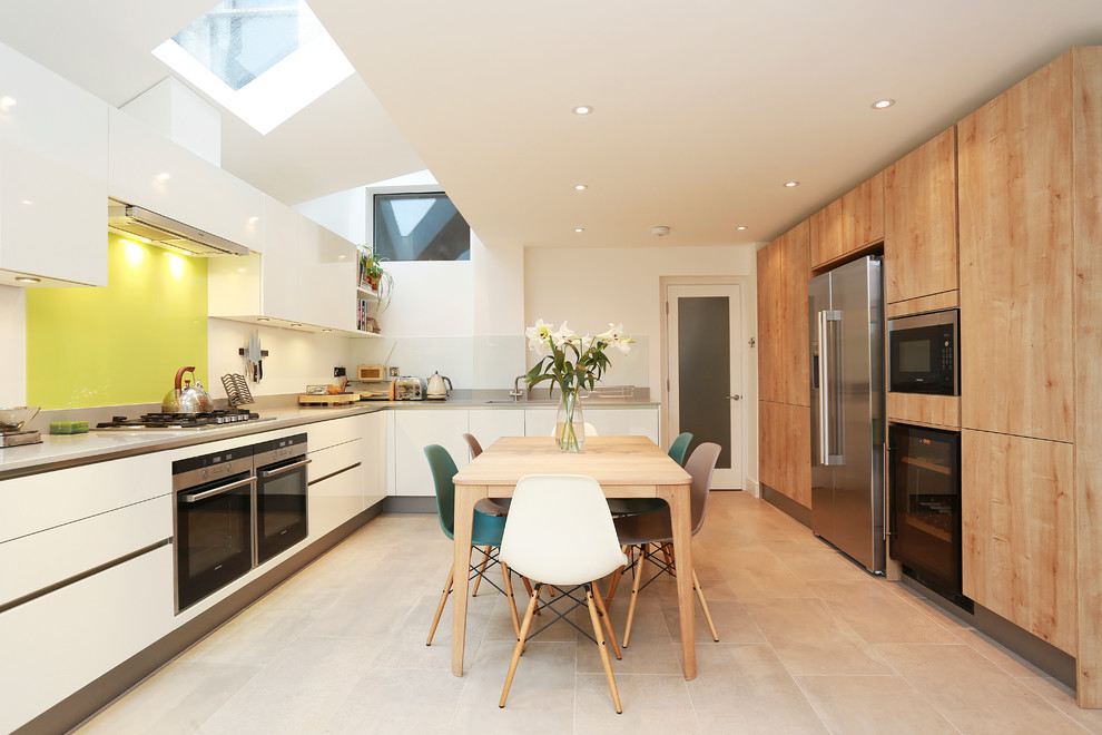 Foto på ett stort funkis kök och matrum, med släta luckor, vita skåp, bänkskiva i kvarts, gult stänkskydd, glaspanel som stänkskydd, integrerade vitvaror och beiget golv