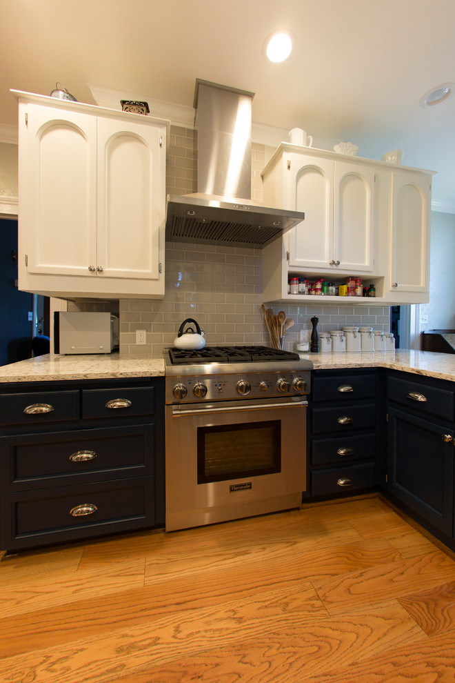 This is an example of a medium sized country galley kitchen/diner in Seattle with a belfast sink, flat-panel cabinets, white cabinets, engineered stone countertops, grey splashback, ceramic splashback, stainless steel appliances, medium hardwood flooring and a breakfast bar.