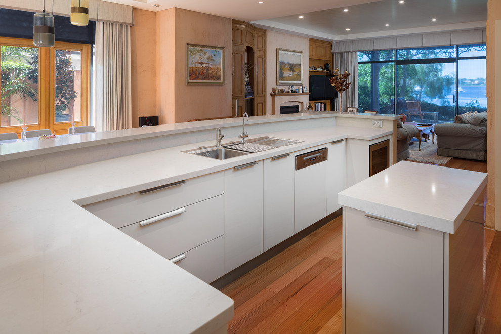 Moderne Küche mit Doppelwaschbecken, flächenbündigen Schrankfronten, grauen Schränken, Quarzwerkstein-Arbeitsplatte, Küchengeräten aus Edelstahl, zwei Kücheninseln und weißer Arbeitsplatte in Perth