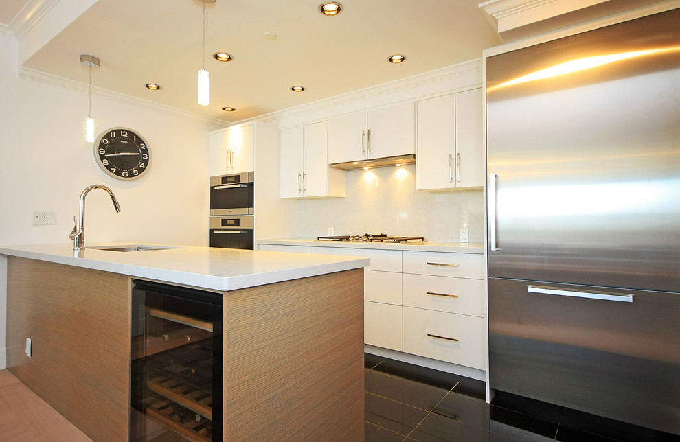 Immagine di una cucina parallela design con ante lisce, ante bianche, top in quarzo composito, paraspruzzi bianco, elettrodomestici in acciaio inossidabile e penisola