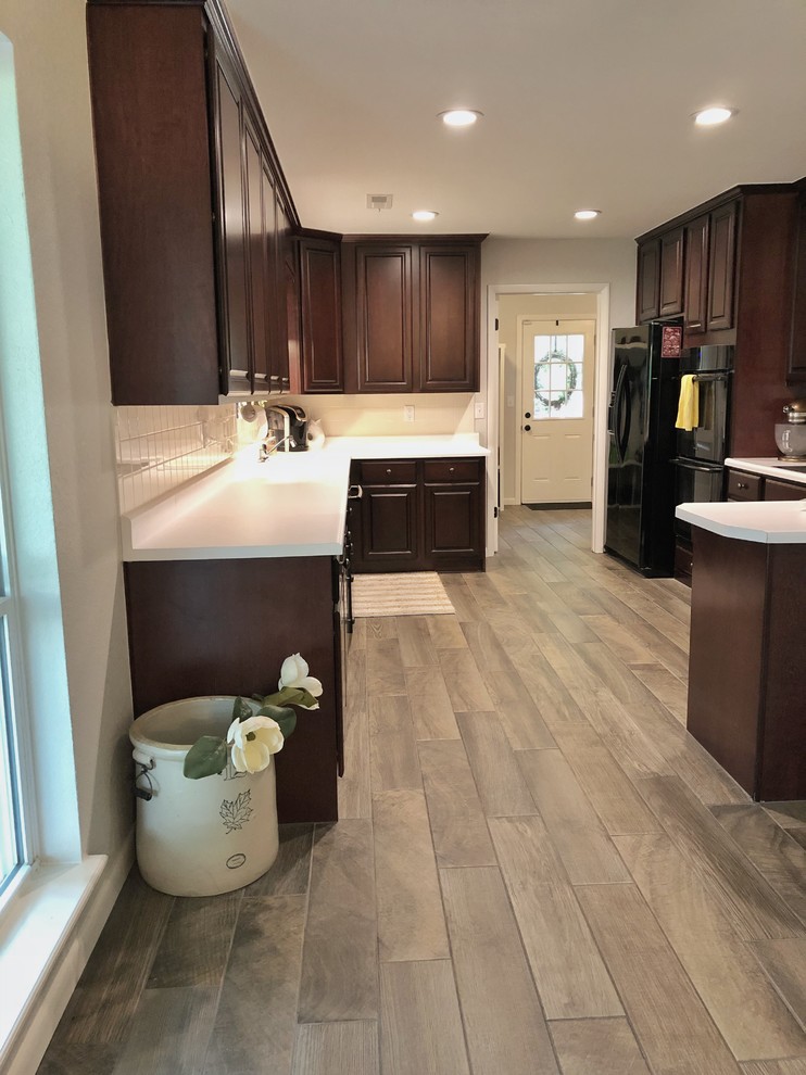 Mid-sized cottage u-shaped medium tone wood floor and brown floor eat-in kitchen photo in Other with an undermount sink, raised-panel cabinets, dark wood cabinets, quartz countertops, white backsplash, ceramic backsplash, black appliances, a peninsula and white countertops
