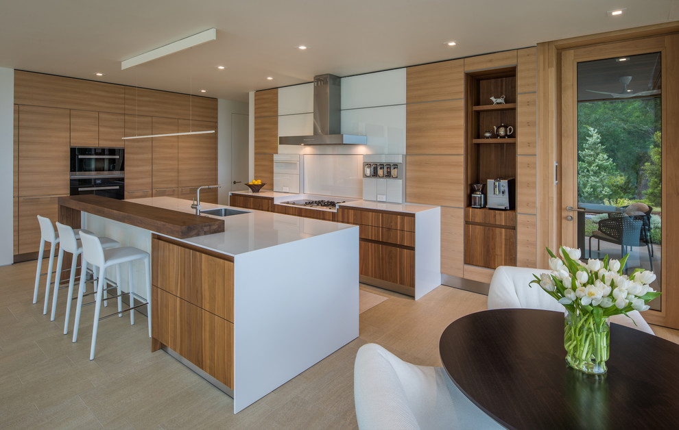 Contemporary l-shaped kitchen/diner in Other with a submerged sink, flat-panel cabinets, medium wood cabinets, quartz worktops, white splashback, glass sheet splashback, stainless steel appliances, porcelain flooring, an island, beige floors and white worktops.