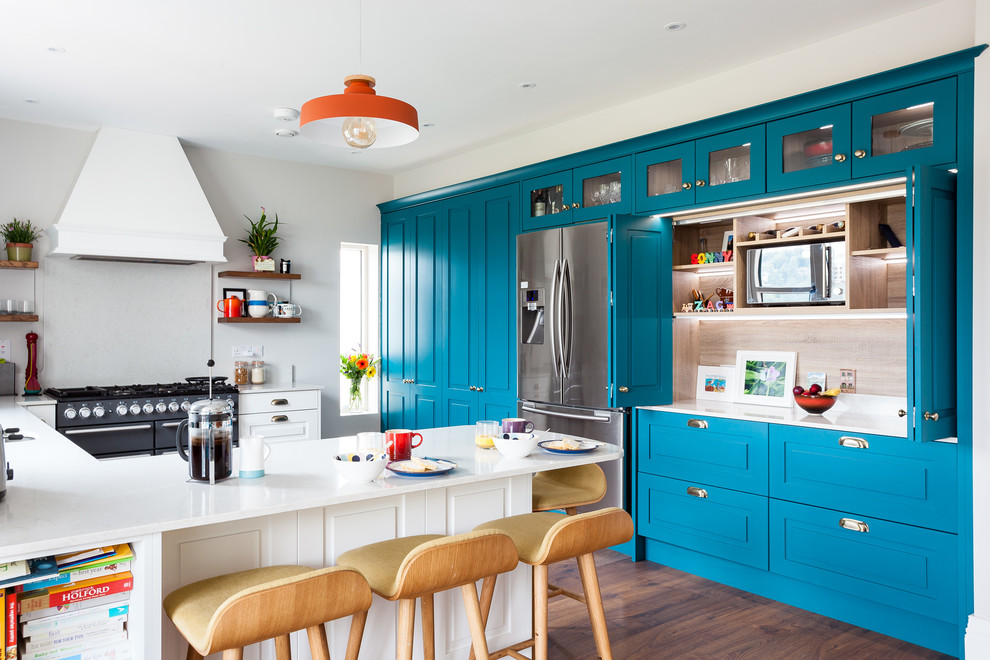Foto di una cucina ad U classica con ante blu, elettrodomestici in acciaio inossidabile, parquet scuro, pavimento marrone e top bianco