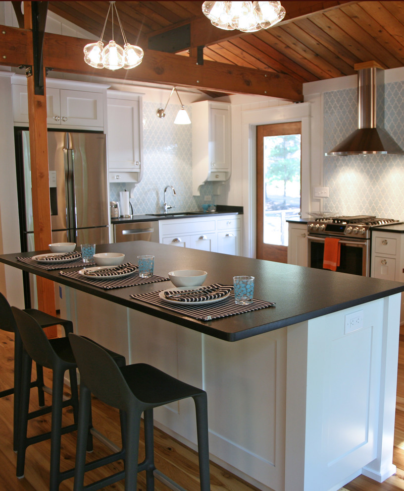 Example of a mid-sized urban light wood floor eat-in kitchen design in Milwaukee with a single-bowl sink, recessed-panel cabinets, white cabinets, granite countertops, blue backsplash, ceramic backsplash, stainless steel appliances and an island