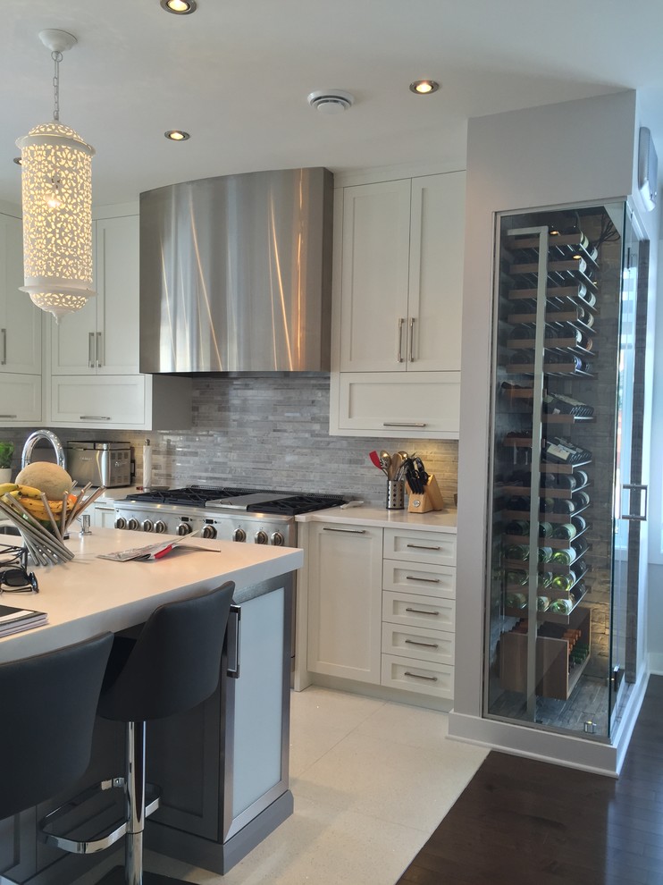 Example of a large trendy u-shaped enclosed kitchen design in Montreal with an undermount sink, shaker cabinets, white cabinets, solid surface countertops, mosaic tile backsplash, stainless steel appliances and an island