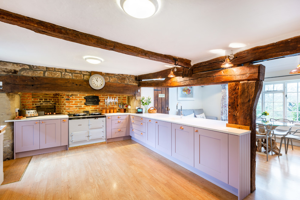Offene Landhaus Küche in L-Form mit Schrankfronten im Shaker-Stil, lila Schränken, Quarzit-Arbeitsplatte und weißer Arbeitsplatte in Sussex