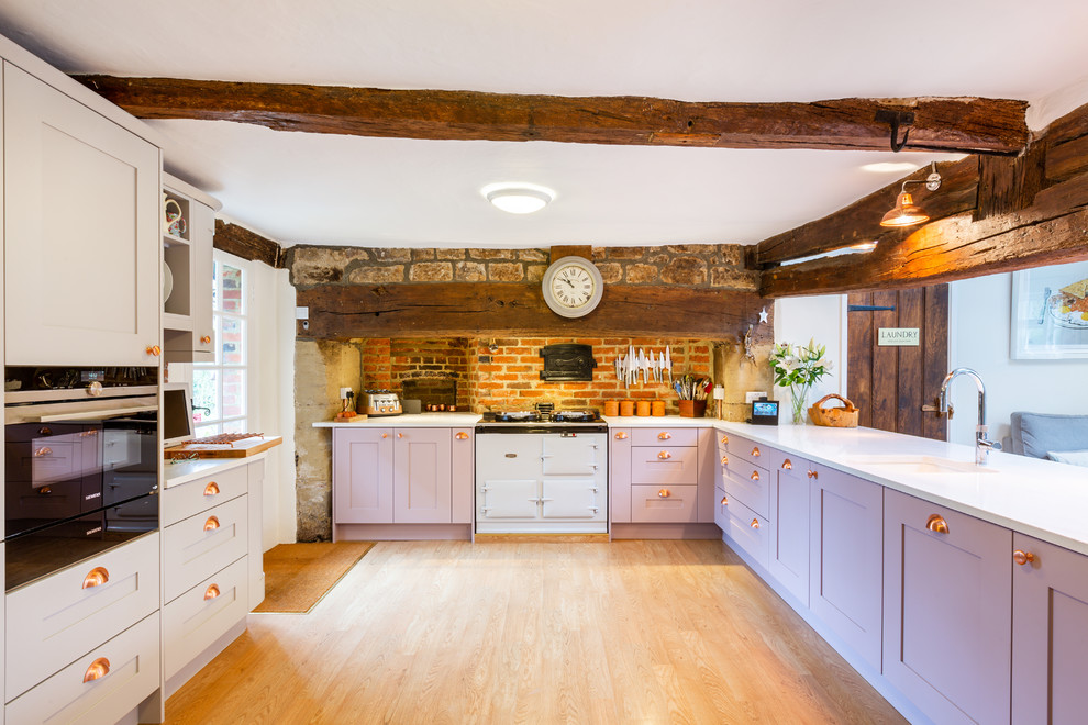 Design ideas for a country l-shaped kitchen in Sussex with shaker cabinets, purple cabinets, quartz worktops, white worktops, brick splashback, black appliances, medium hardwood flooring and no island.