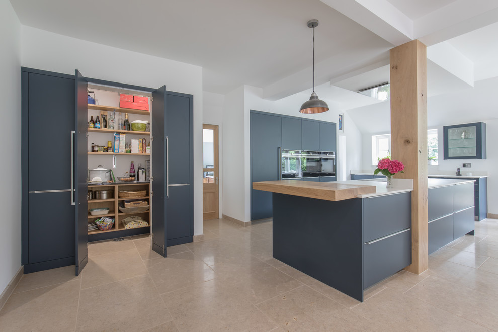 Photo of a large contemporary open plan kitchen in Sussex with an integrated sink, flat-panel cabinets, blue cabinets, engineered stone countertops, stainless steel appliances, limestone flooring, an island and beige floors.