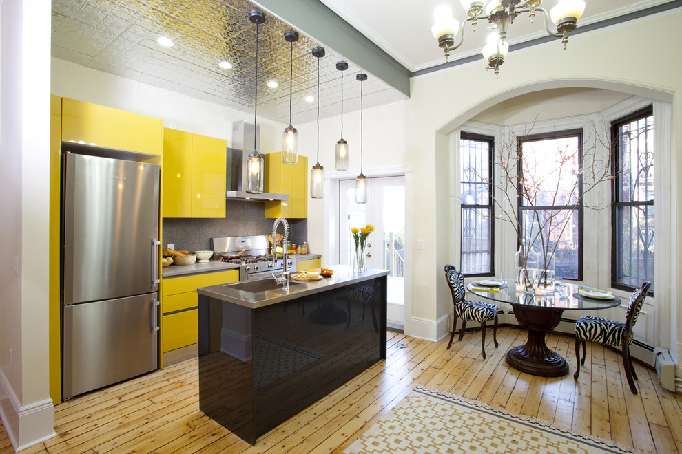 Zweizeilige Moderne Wohnküche mit integriertem Waschbecken, flächenbündigen Schrankfronten, gelben Schränken, Edelstahl-Arbeitsplatte, Küchenrückwand in Grau und Küchengeräten aus Edelstahl in New York