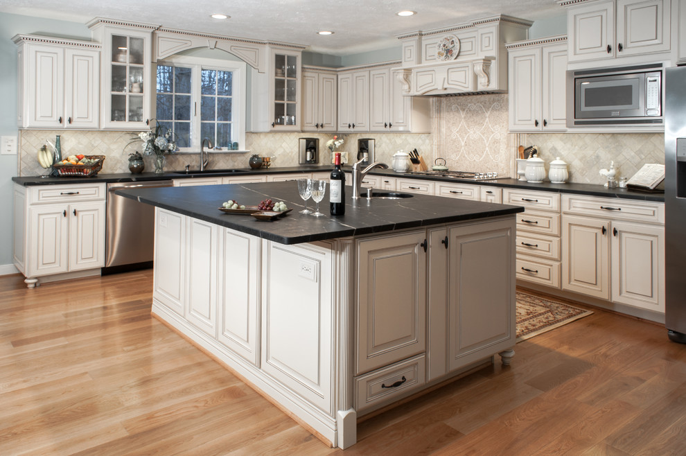 Large elegant l-shaped medium tone wood floor eat-in kitchen photo in Richmond with an undermount sink, raised-panel cabinets, white cabinets, soapstone countertops, beige backsplash, mosaic tile backsplash, stainless steel appliances and an island