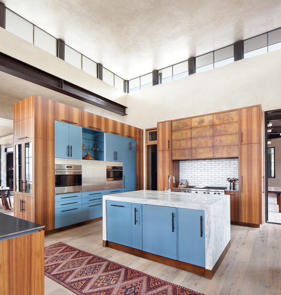 Exempel på ett mycket stort modernt l-kök, med släta luckor, marmorbänkskiva, vitt stänkskydd, stänkskydd i keramik, rostfria vitvaror, ljust trägolv, en köksö, beiget golv och blå skåp