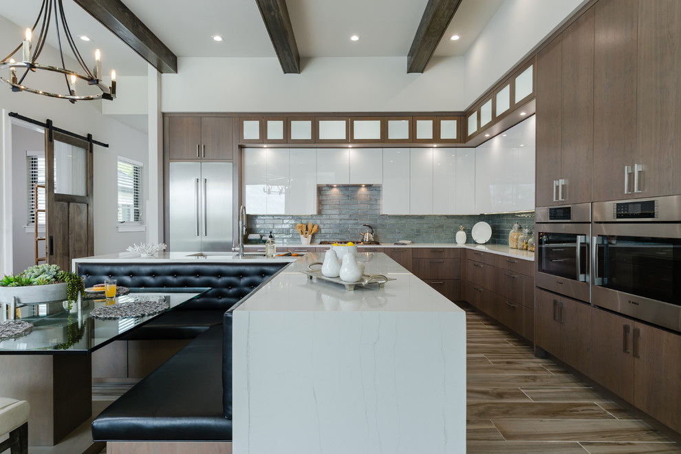 Contemporary l-shaped kitchen/diner in Tampa with a submerged sink, flat-panel cabinets, medium wood cabinets, engineered stone countertops, blue splashback, glass tiled splashback, stainless steel appliances, an island, multi-coloured floors and white worktops.