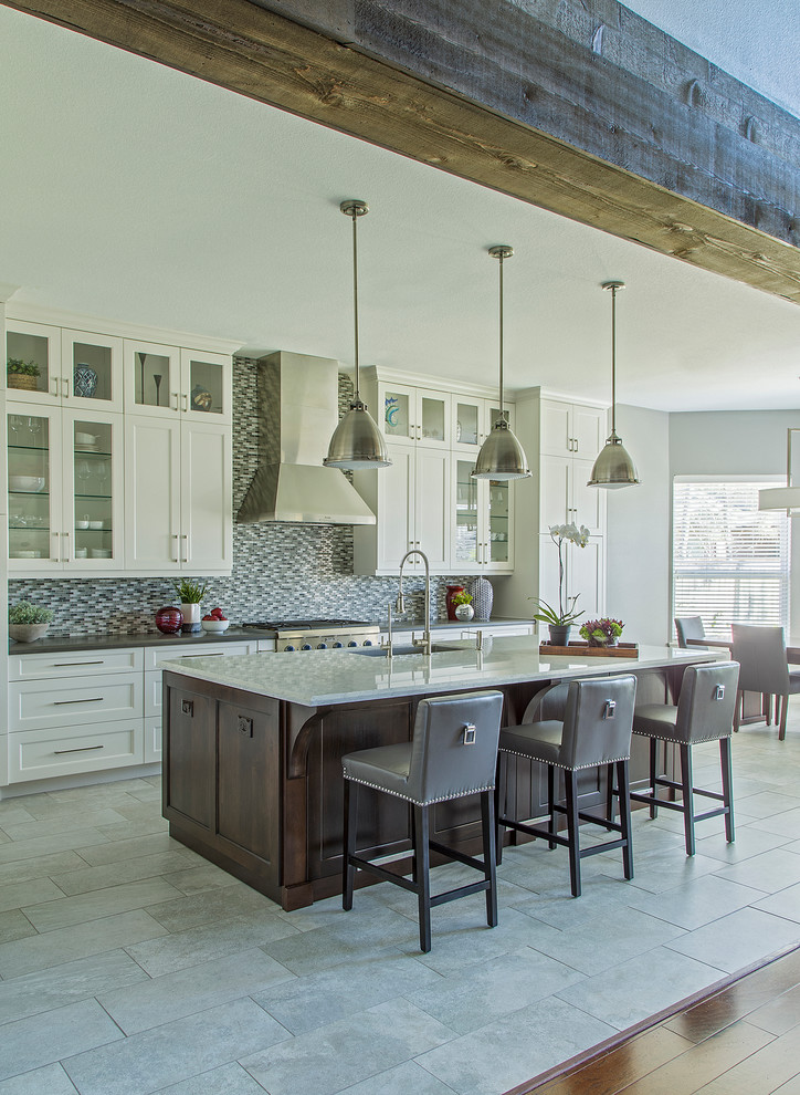 Example of a mid-sized country l-shaped porcelain tile and gray floor eat-in kitchen design in Other with an undermount sink, recessed-panel cabinets, white cabinets, quartz countertops, gray backsplash, glass tile backsplash, stainless steel appliances and an island