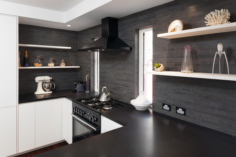 Foto på ett stort funkis kök, med vita skåp, granitbänkskiva, svart stänkskydd, stänkskydd i keramik, svarta vitvaror, mellanmörkt trägolv och en köksö