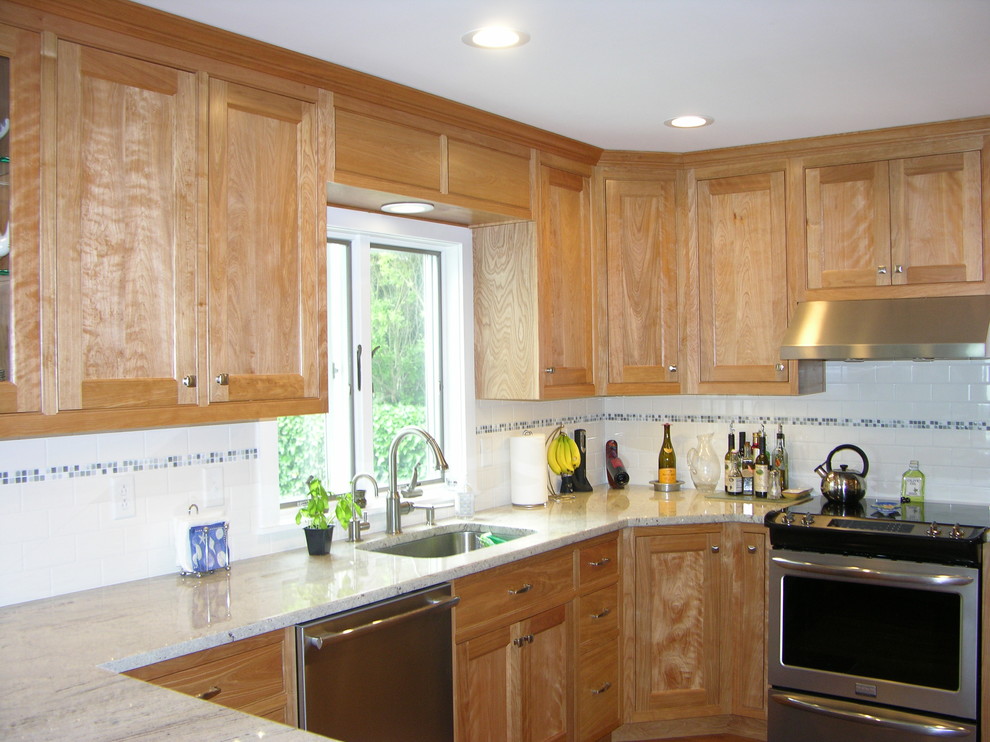 Cette image montre une petite cuisine américaine traditionnelle en U et bois brun avec un placard à porte affleurante, un plan de travail en granite, une crédence blanche, un sol en bois brun et une péninsule.