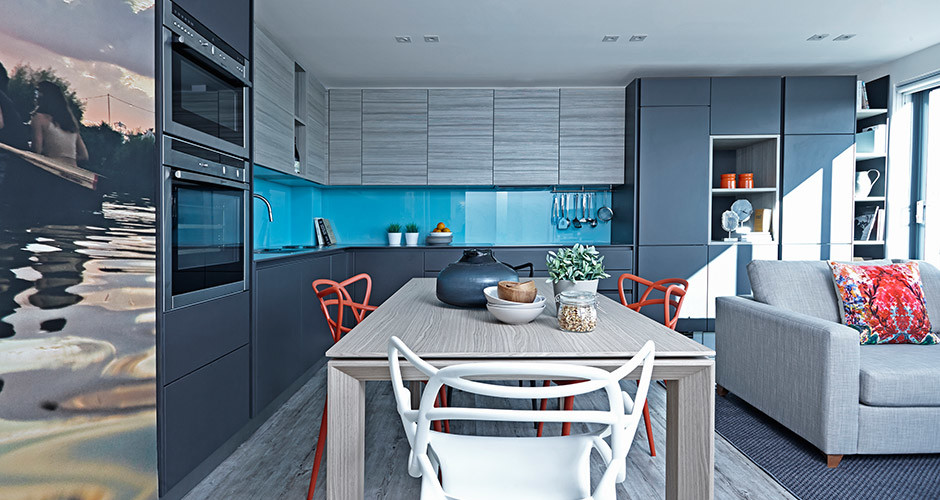 This is an example of a contemporary open plan kitchen in London with a submerged sink, grey cabinets, blue splashback, glass sheet splashback, integrated appliances, light hardwood flooring, no island and flat-panel cabinets.