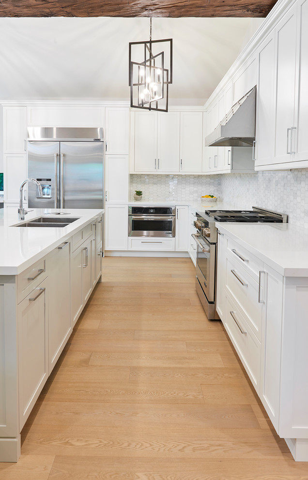 This is an example of a large classic l-shaped kitchen in Toronto with a double-bowl sink, shaker cabinets, white cabinets, wood worktops, white splashback, mosaic tiled splashback, stainless steel appliances, light hardwood flooring, an island, beige floors and white worktops.